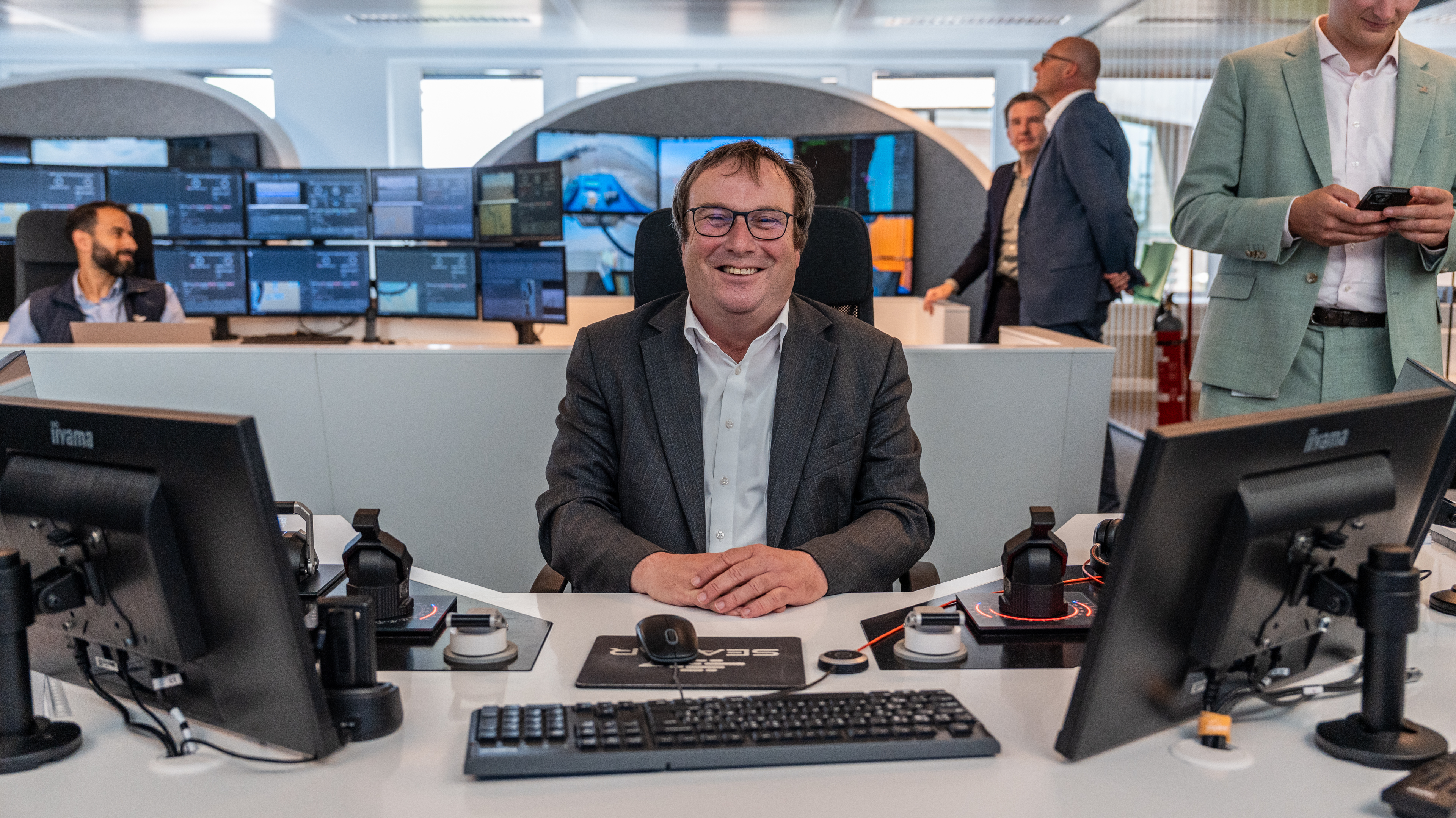 Minister Oliver Krischer an einem Seafar-Remote-Operator-Arbeitsplatz, umgeben von Tastaturen und Bildschirmen