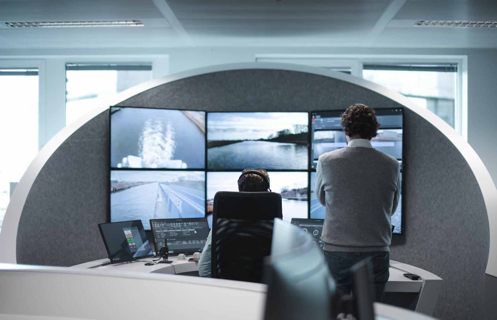 A remote operator being trained at a workstation in a Seafar Remote Operations Center, observing live vessel camera feeds and navigation data on a curved monitor wall