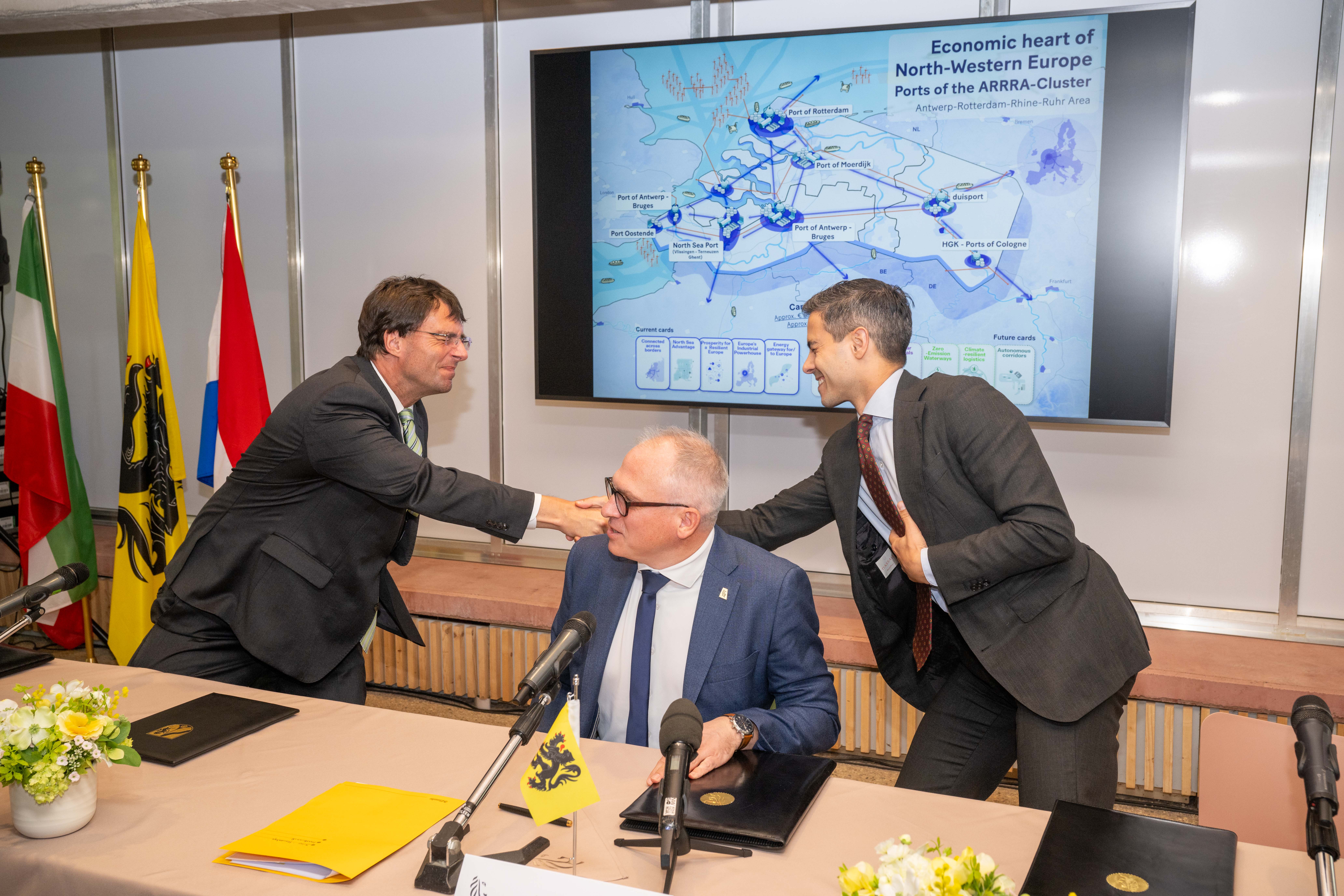 Regeringsvertegenwoordigers bij de ondertekening van de Port Summit-verklaring, met achter hen een kaart van het ARRRA-havencluster