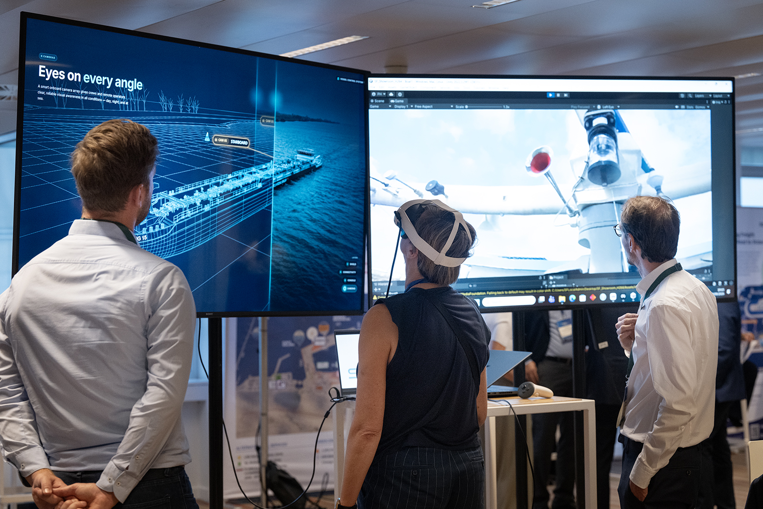 Visitors inspecting vessel camera views and a digital vessel model during a remote operations demonstration